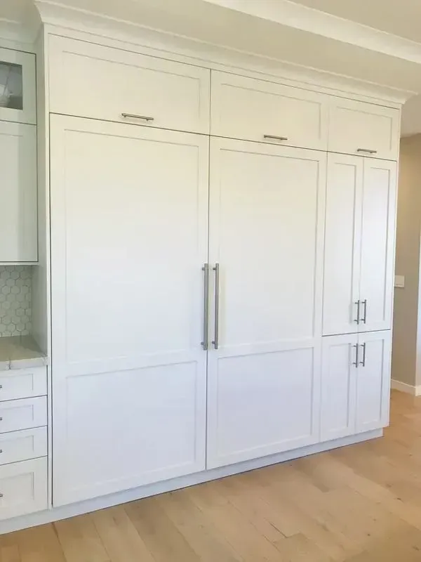 A kitchen with white cabinets and a large refrigerator freezer.