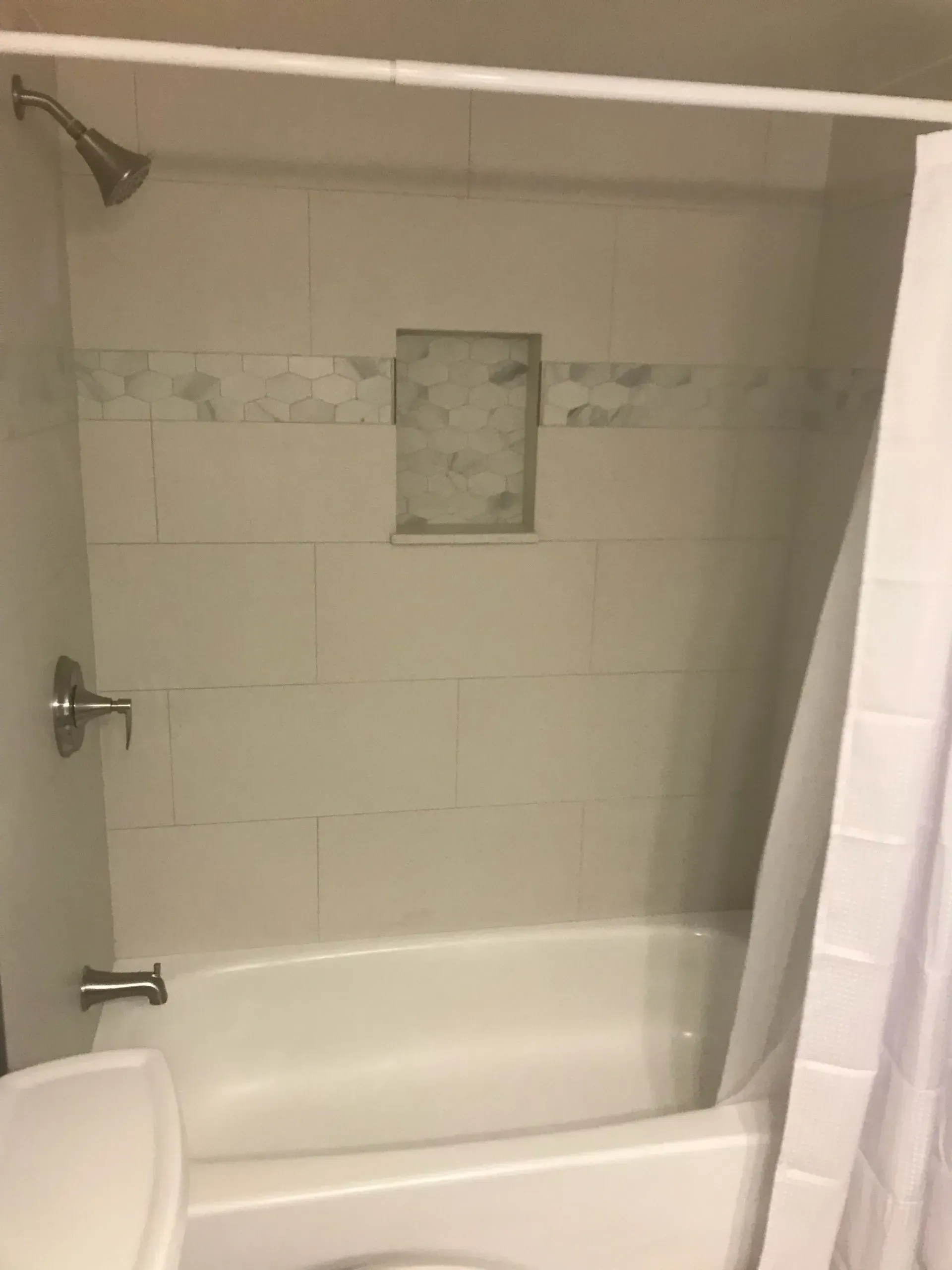 A bathroom with a bathtub , toilet and shower.