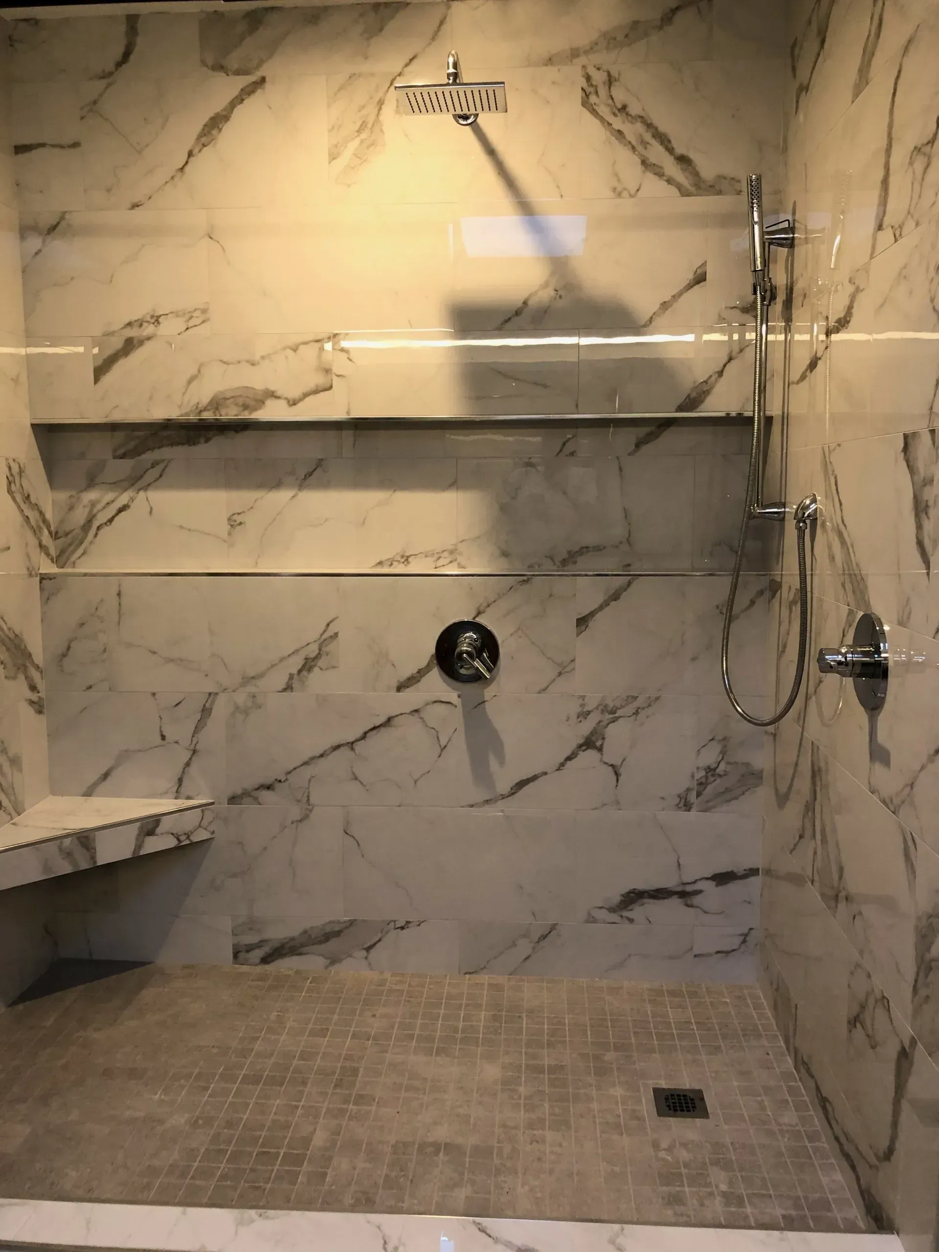 A bathroom with marble walls and a walk in shower