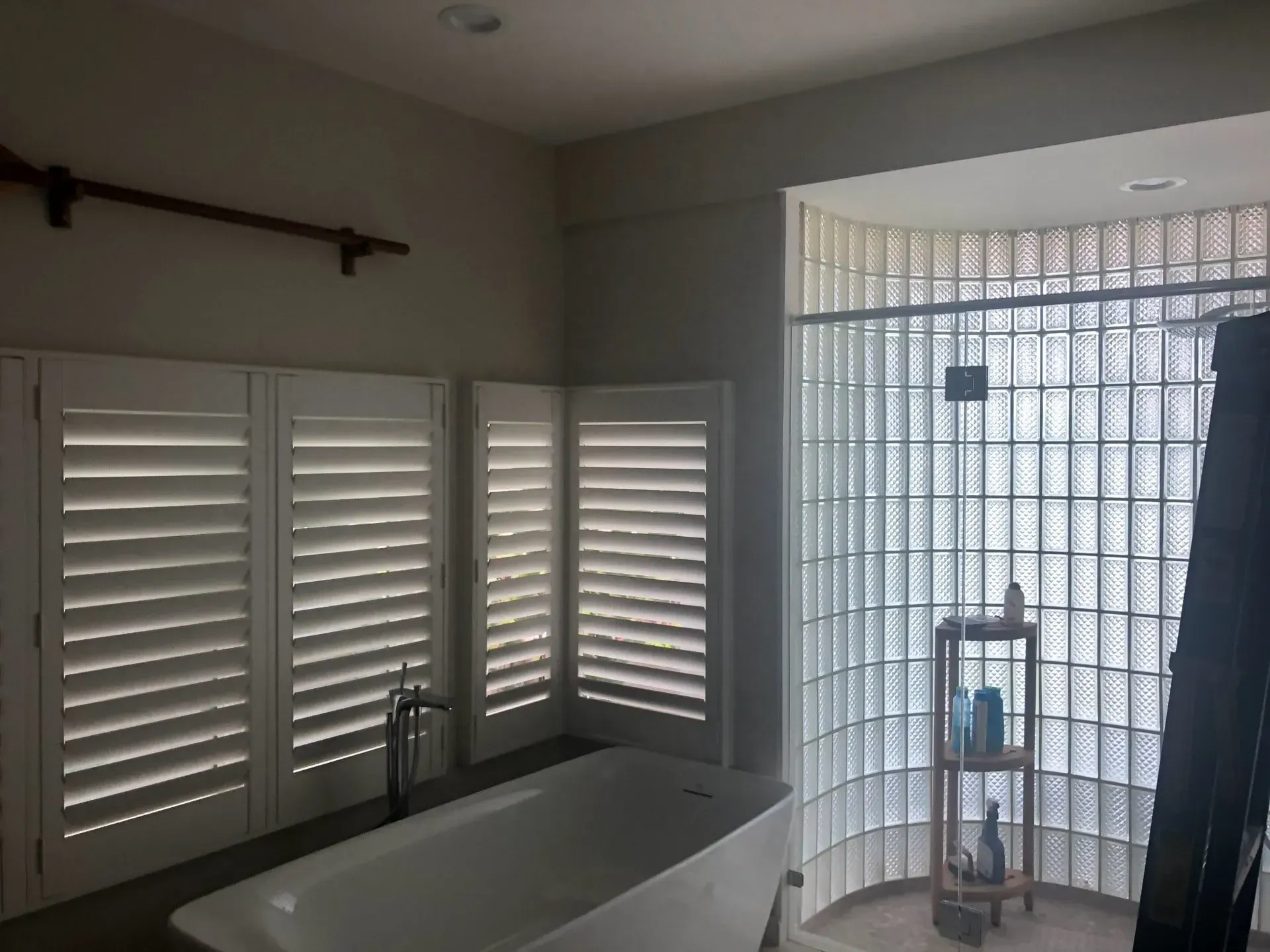 A bathtub in a bathroom with shutters on the windows