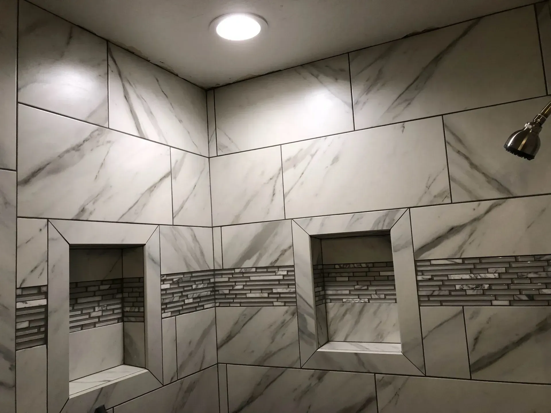 A bathroom with marble tiles and a shower head