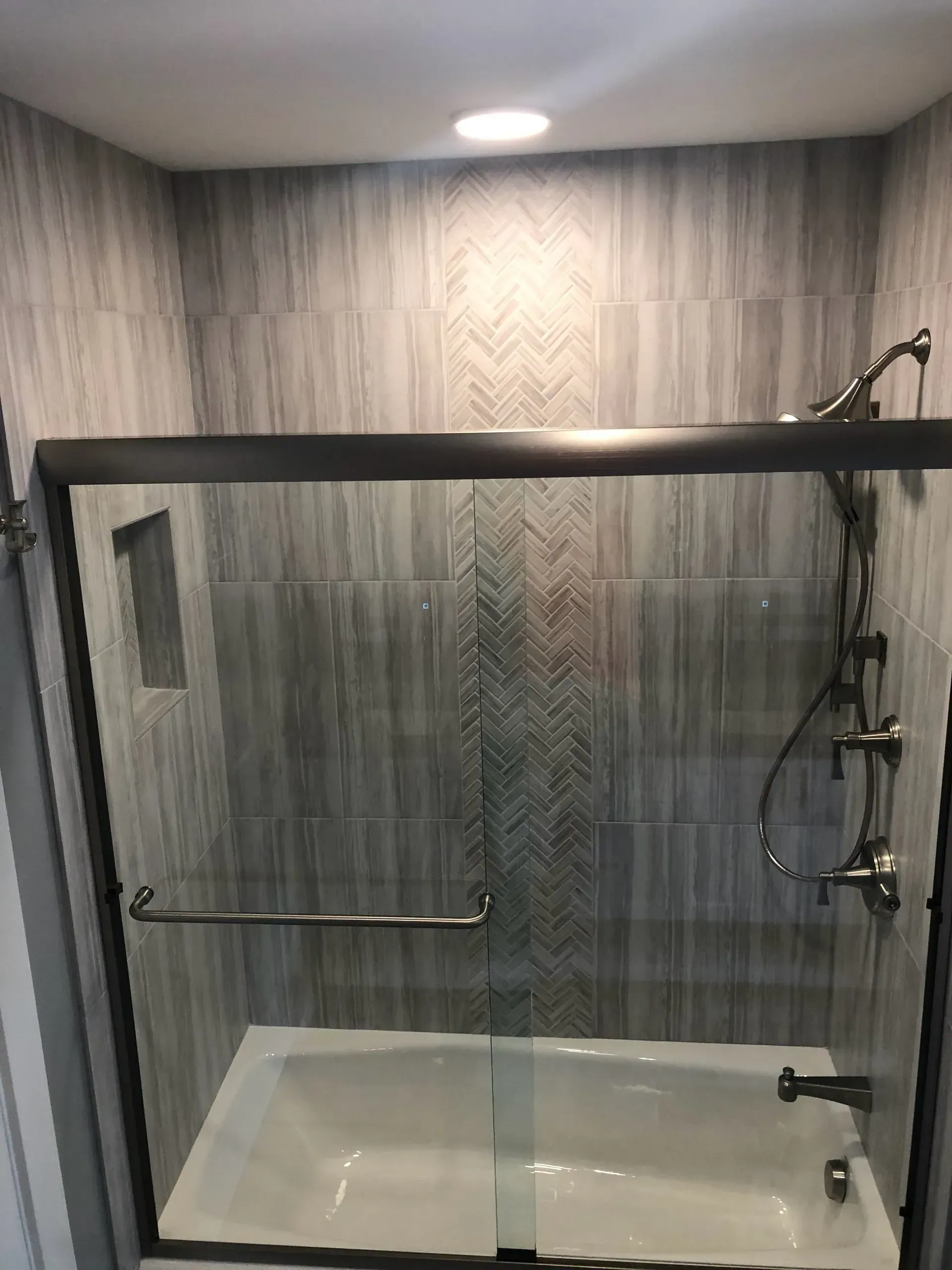 A bathroom with a bathtub and a shower with a sliding glass door.