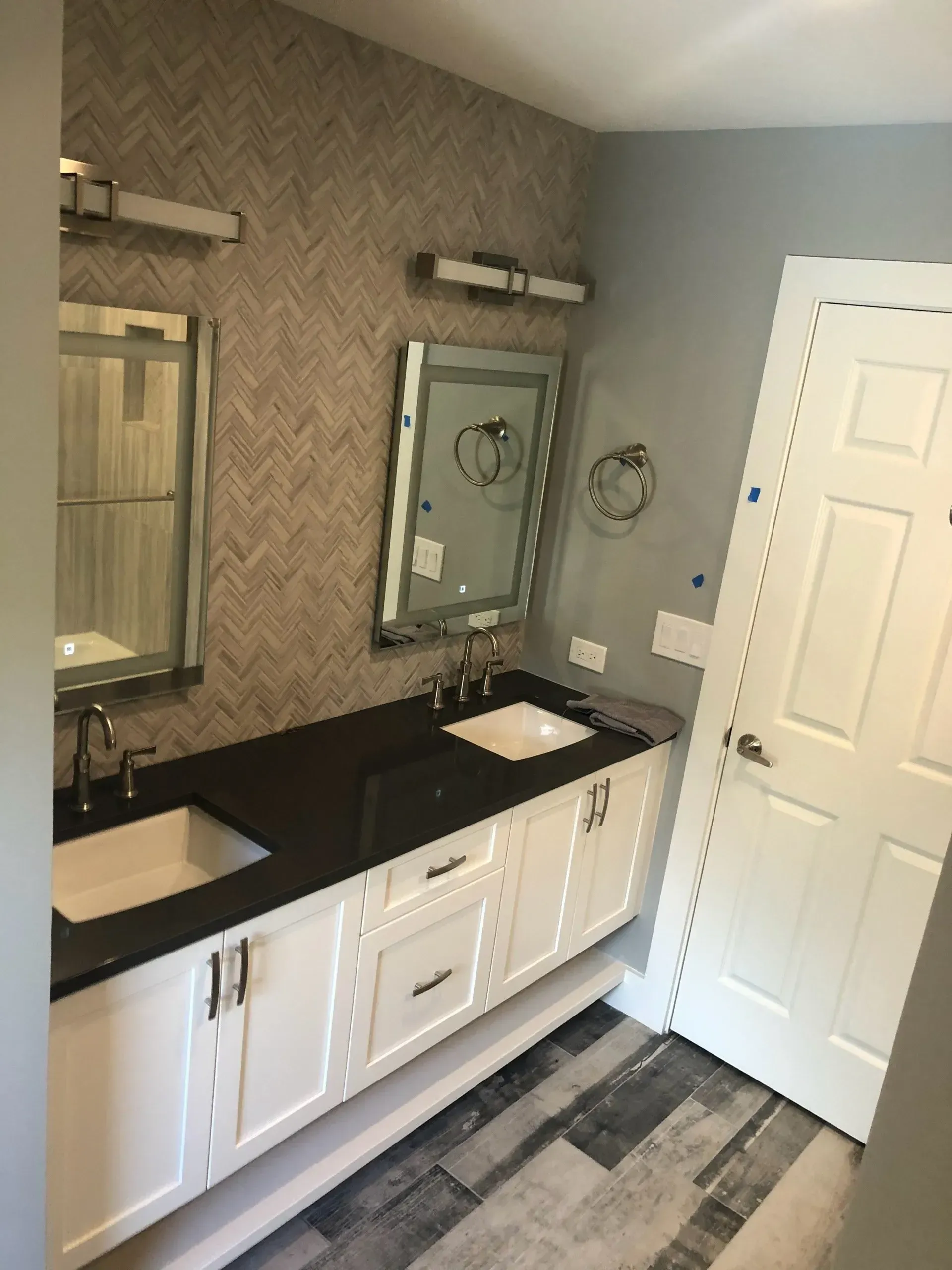 A bathroom with black counter tops and white cabinets