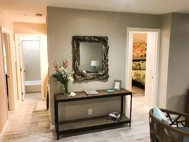 A living room with a table and a mirror on the wall.