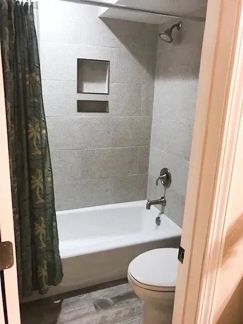 A bathroom with a tub , toilet and shower.
