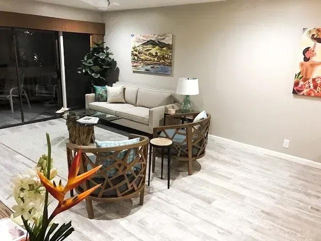 A living room with a couch and chairs and a painting on the wall