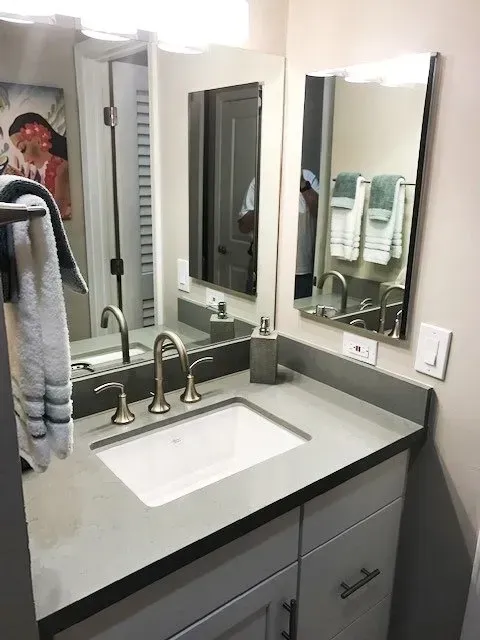 A bathroom with a sink and two mirrors