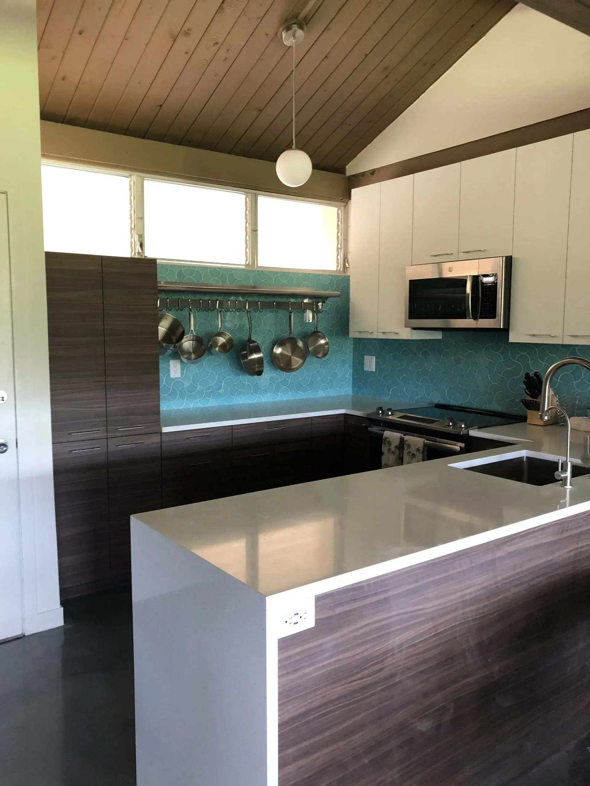 Modern kitchen with white and dark brown cabinets, blue backsplash, and a white countertop island.
