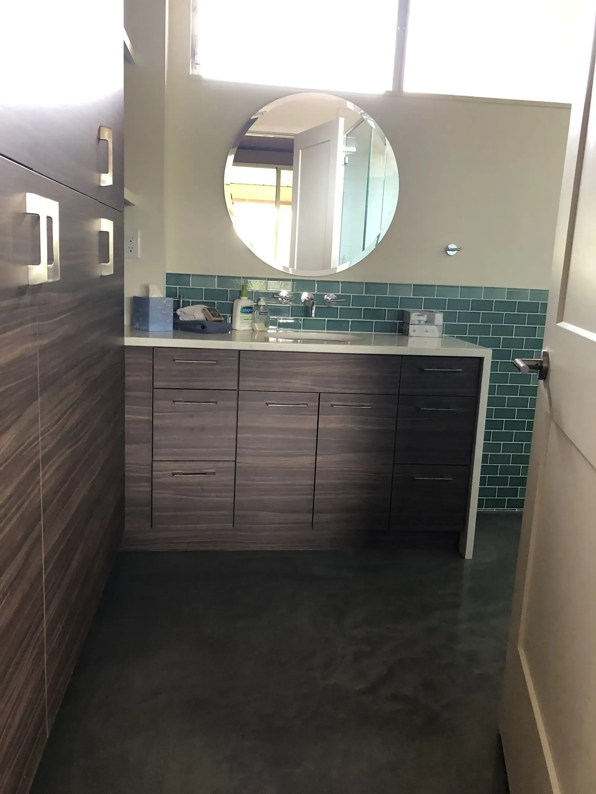 A bathroom with a sink and a round mirror