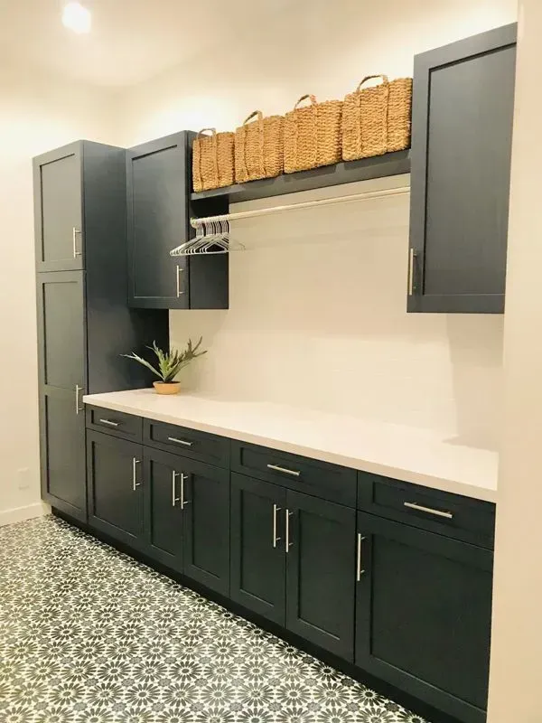 A laundry room with blue cabinets and white counter tops.
