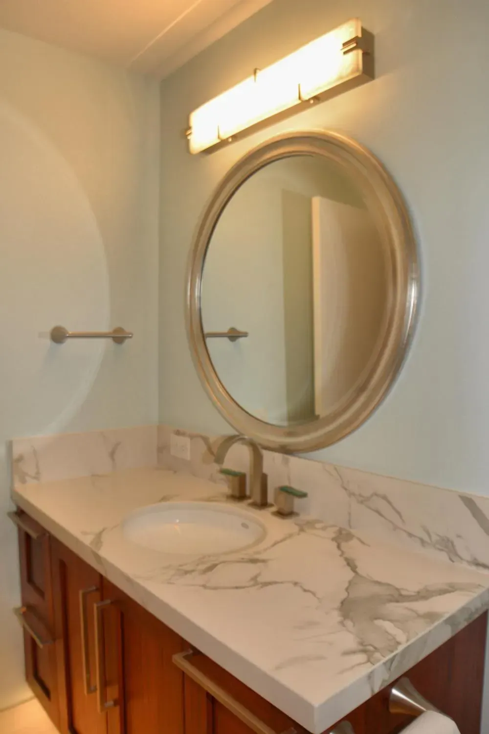 A bathroom sink with a round mirror above it