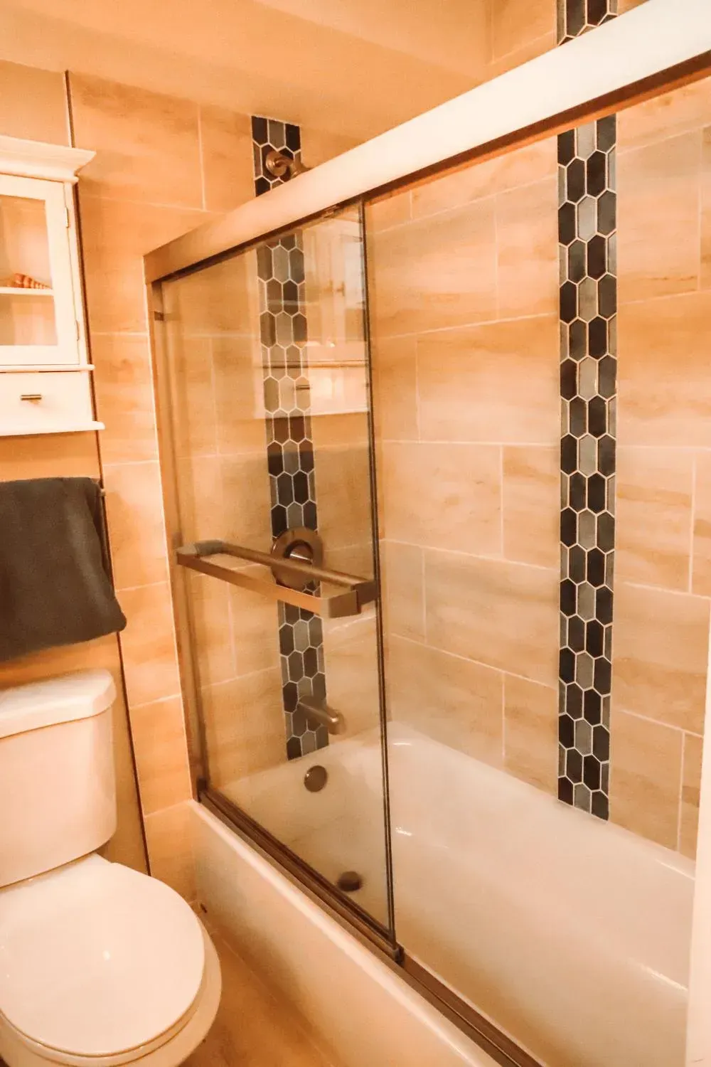 A bathroom with a toilet , tub and shower with sliding glass doors.