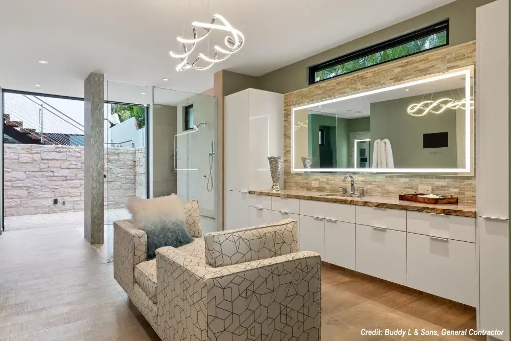 A bathroom with a large mirror and a chair.