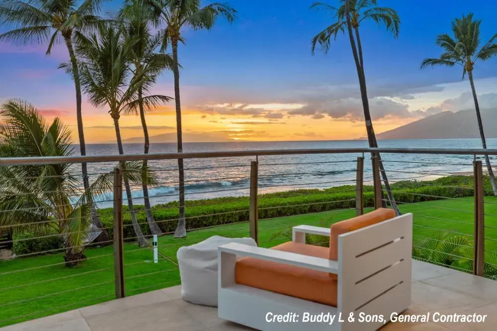 A chair is sitting on a balcony overlooking the ocean at sunset.