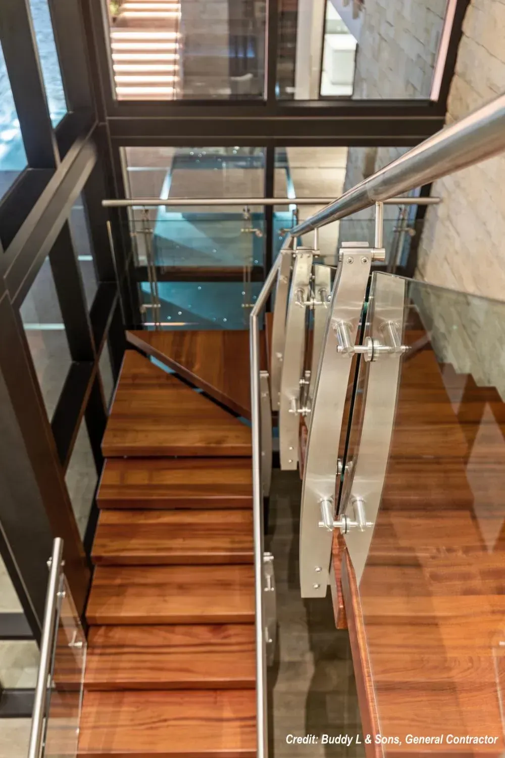 A wooden staircase with a glass railing in a building.