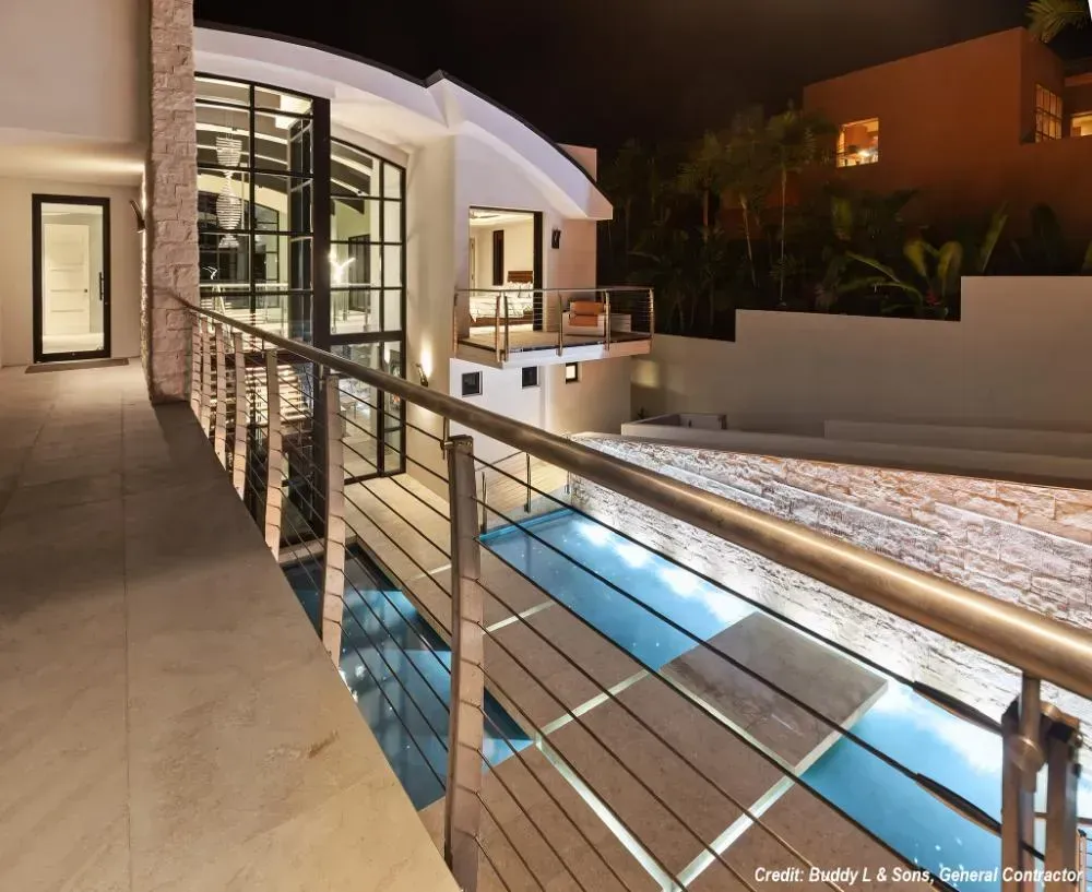 A balcony overlooking a swimming pool with a stainless steel railing