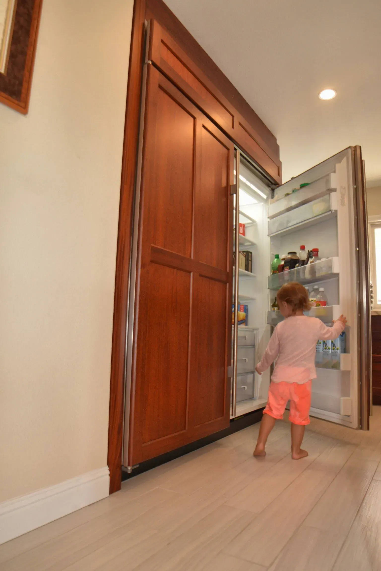 A little girl is standing in front of an open refrigerator