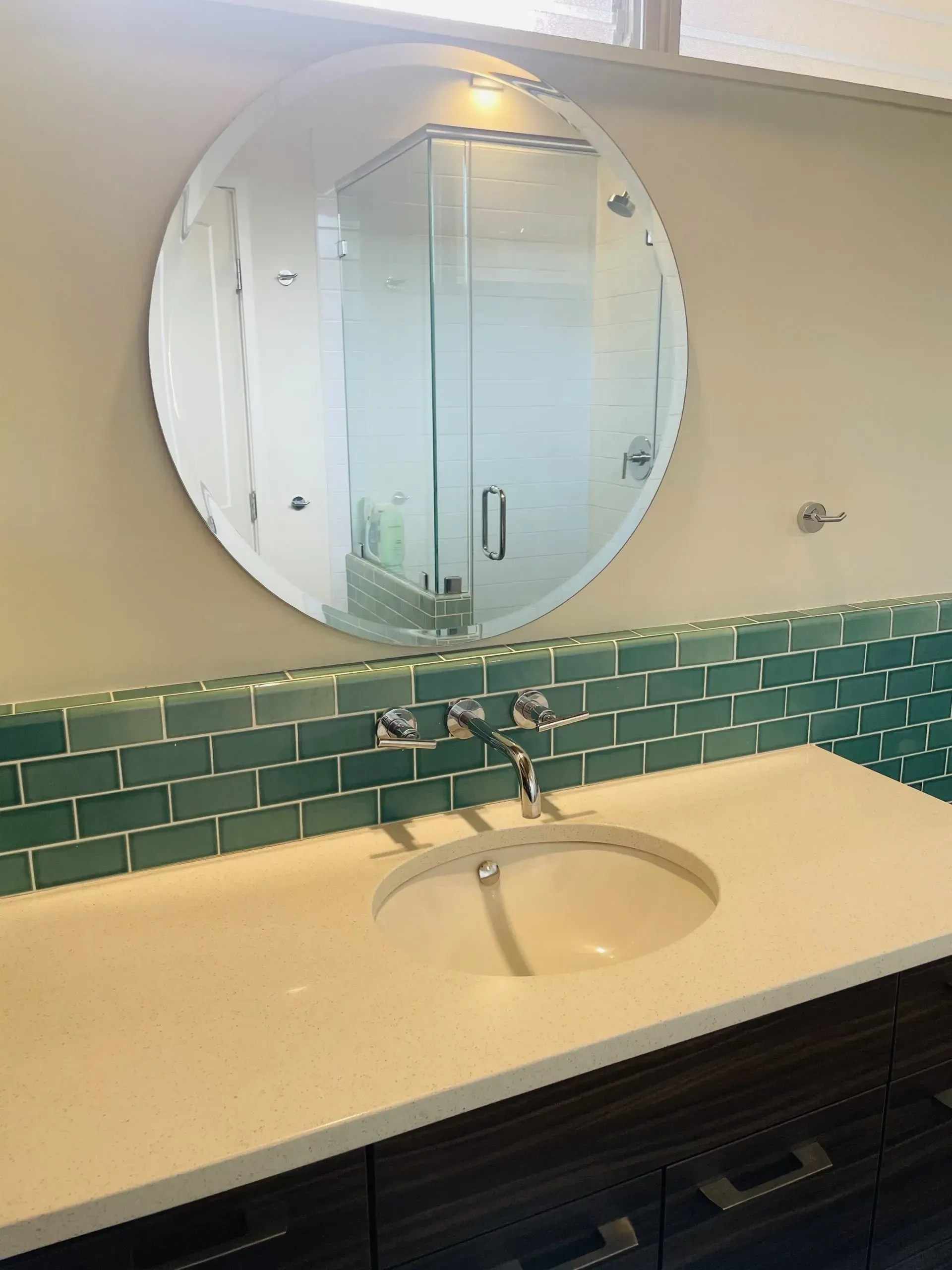 A bathroom with a sink and a round mirror