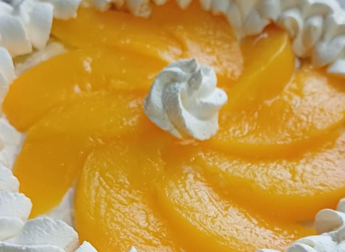 Pastel de melocotón con espirales de crema batida. Rodajas de melocotón dispuestas en espiral.