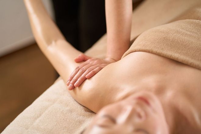 A woman is laying on a bed getting a massage.