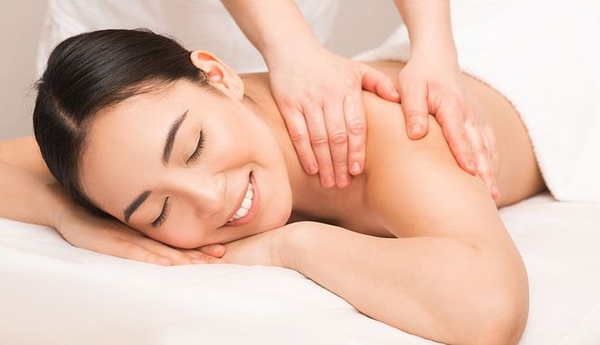 A woman is smiling while getting a massage at a spa.