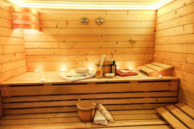 A wooden sauna with a bucket , towels , and candles.