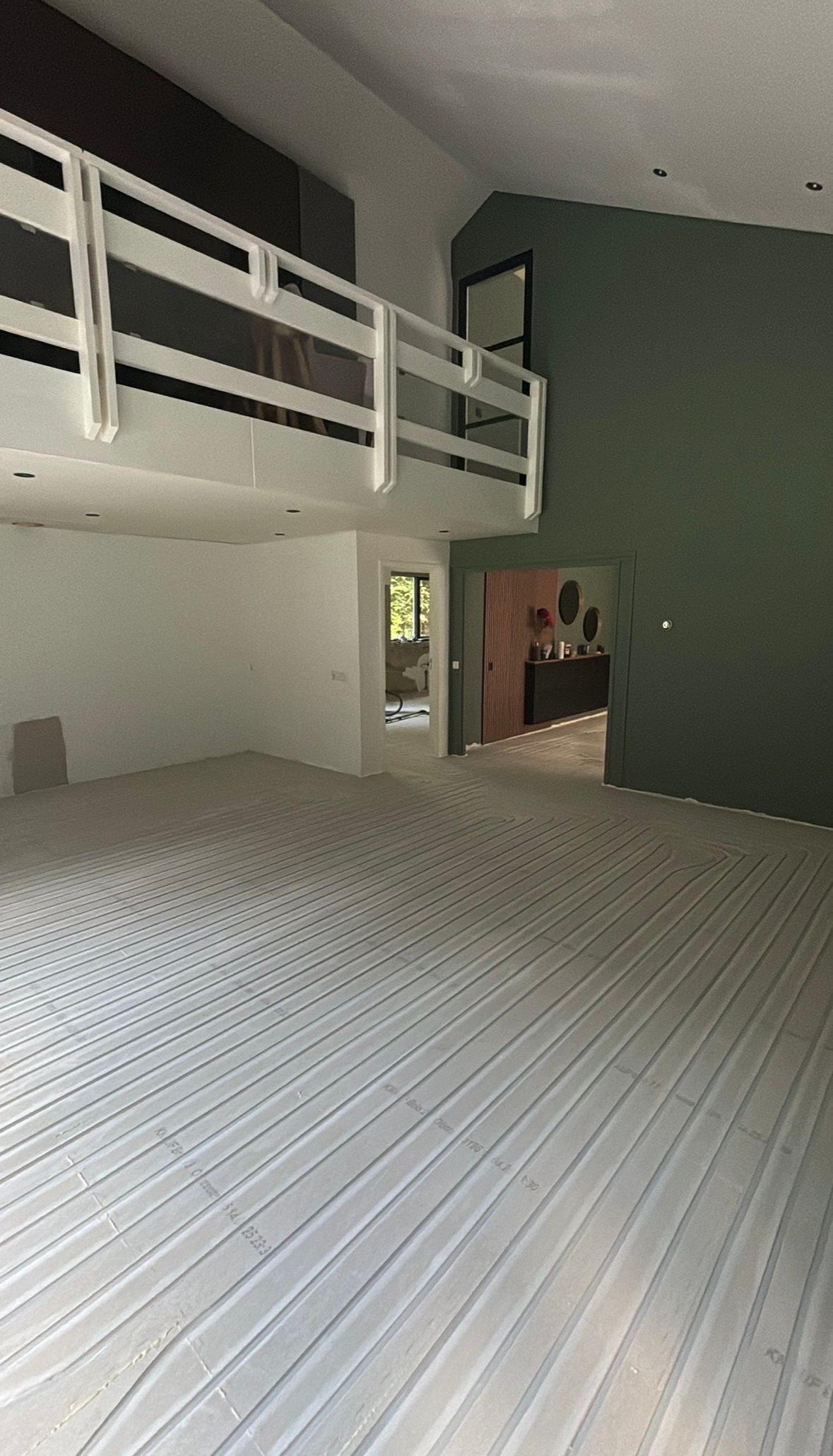 Lege woonkamer met witte balustrade, hoog plafond en lichtgekleurd tapijt.