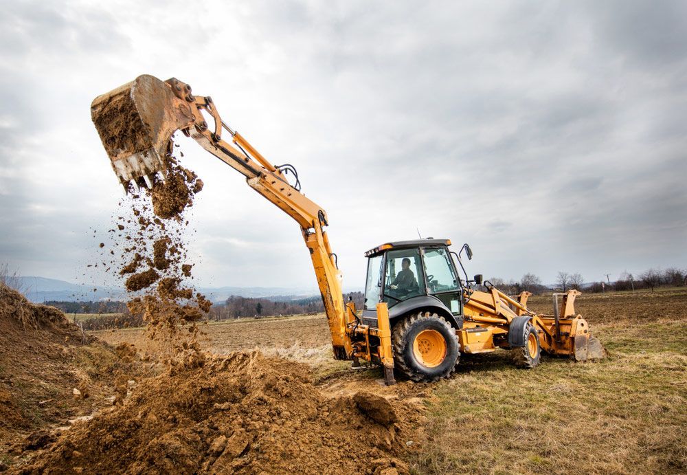 excavator operating in Gladstone, lifting sandy soil on a rural site during earthworks