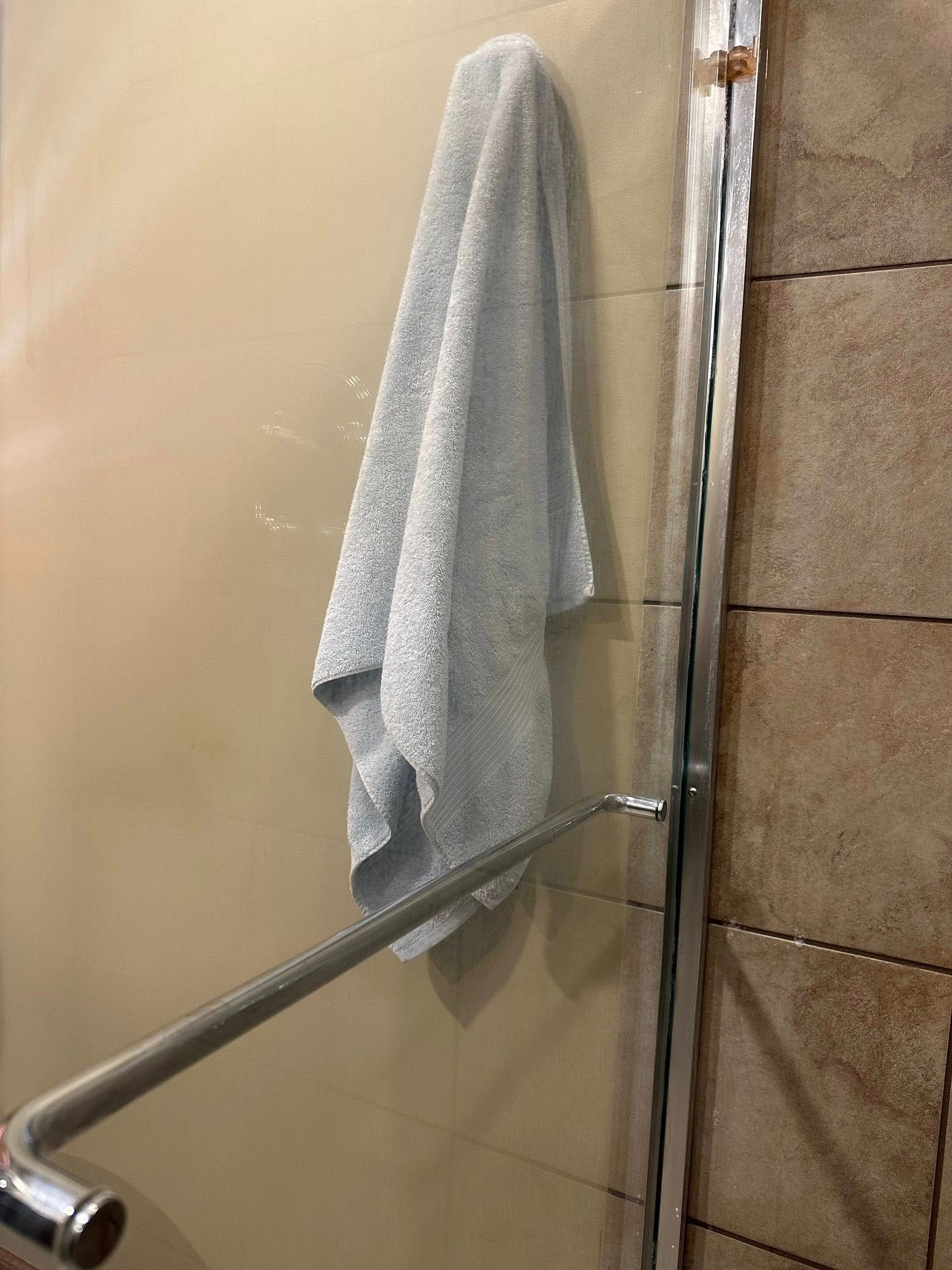 Gray towel hanging on glass shower door.