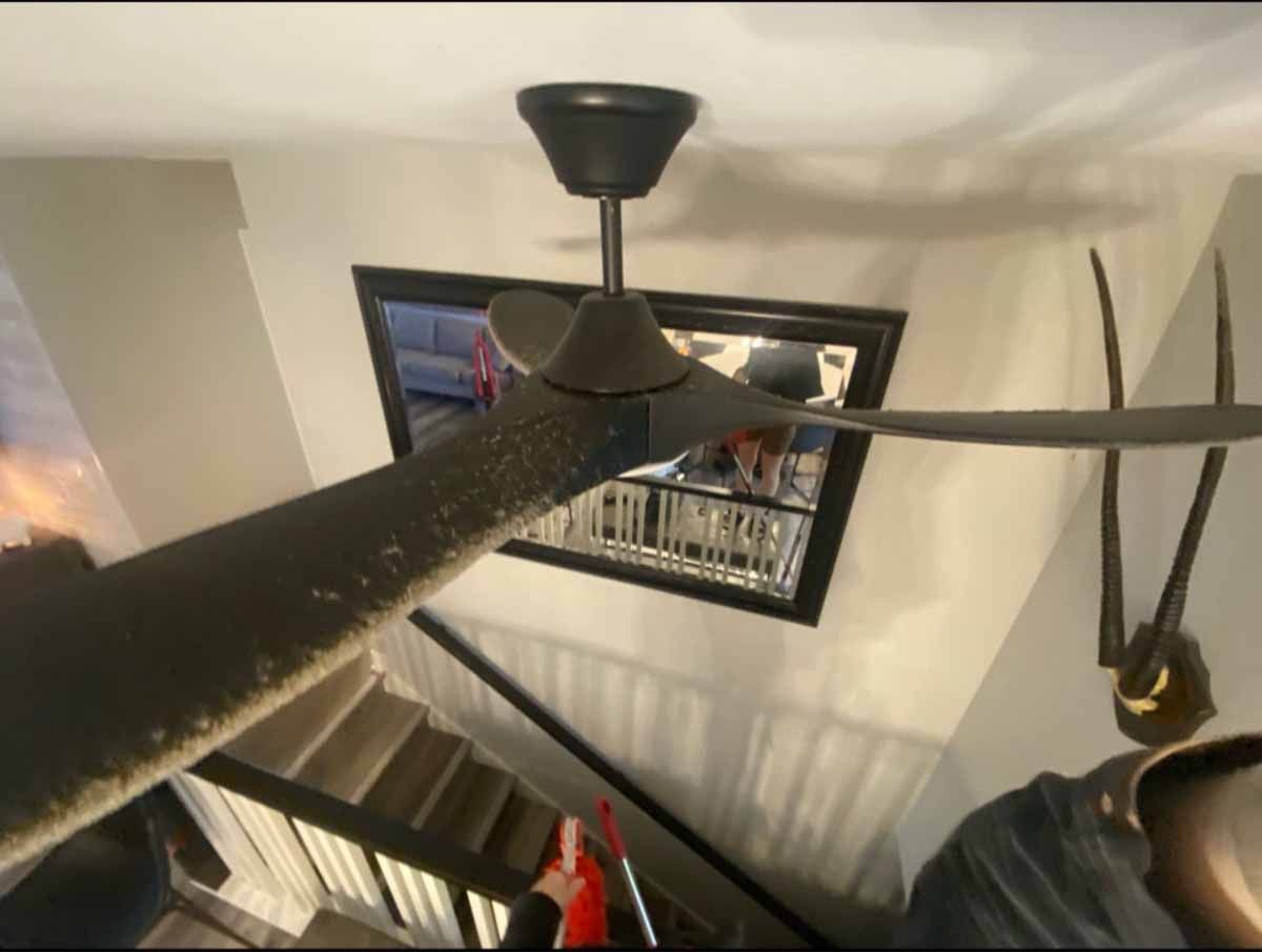 Ceiling fan, black, angled view. Staircase, mirror, and decorations visible.