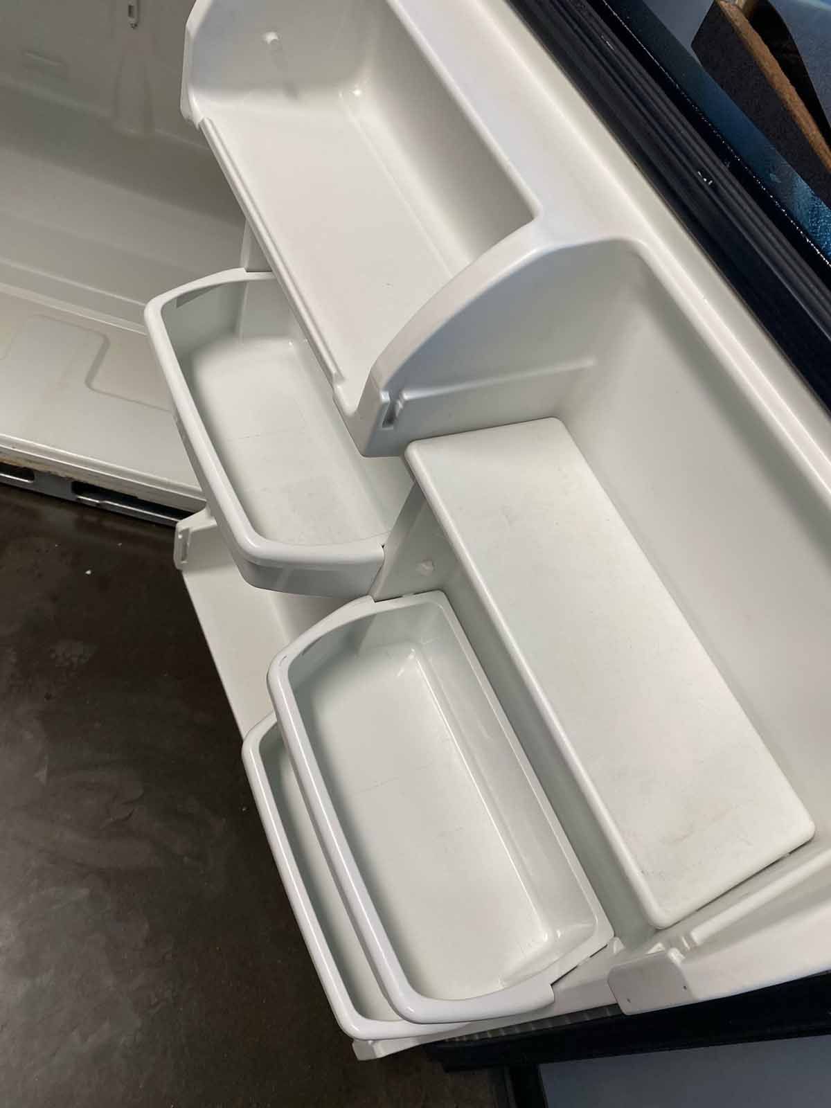 White refrigerator door with open bins, angled view.