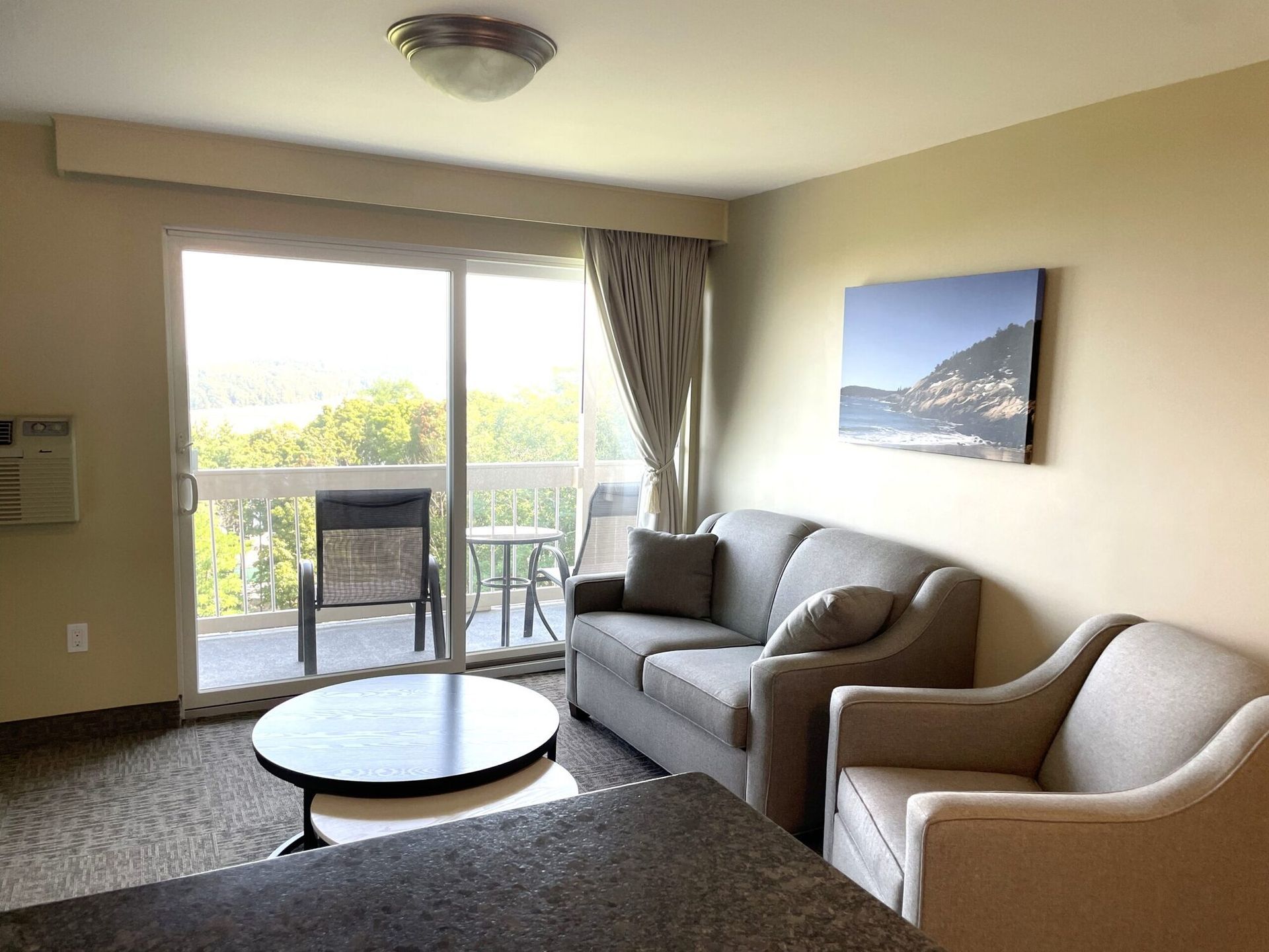 A living room with a couch , chairs , a table and a balcony.