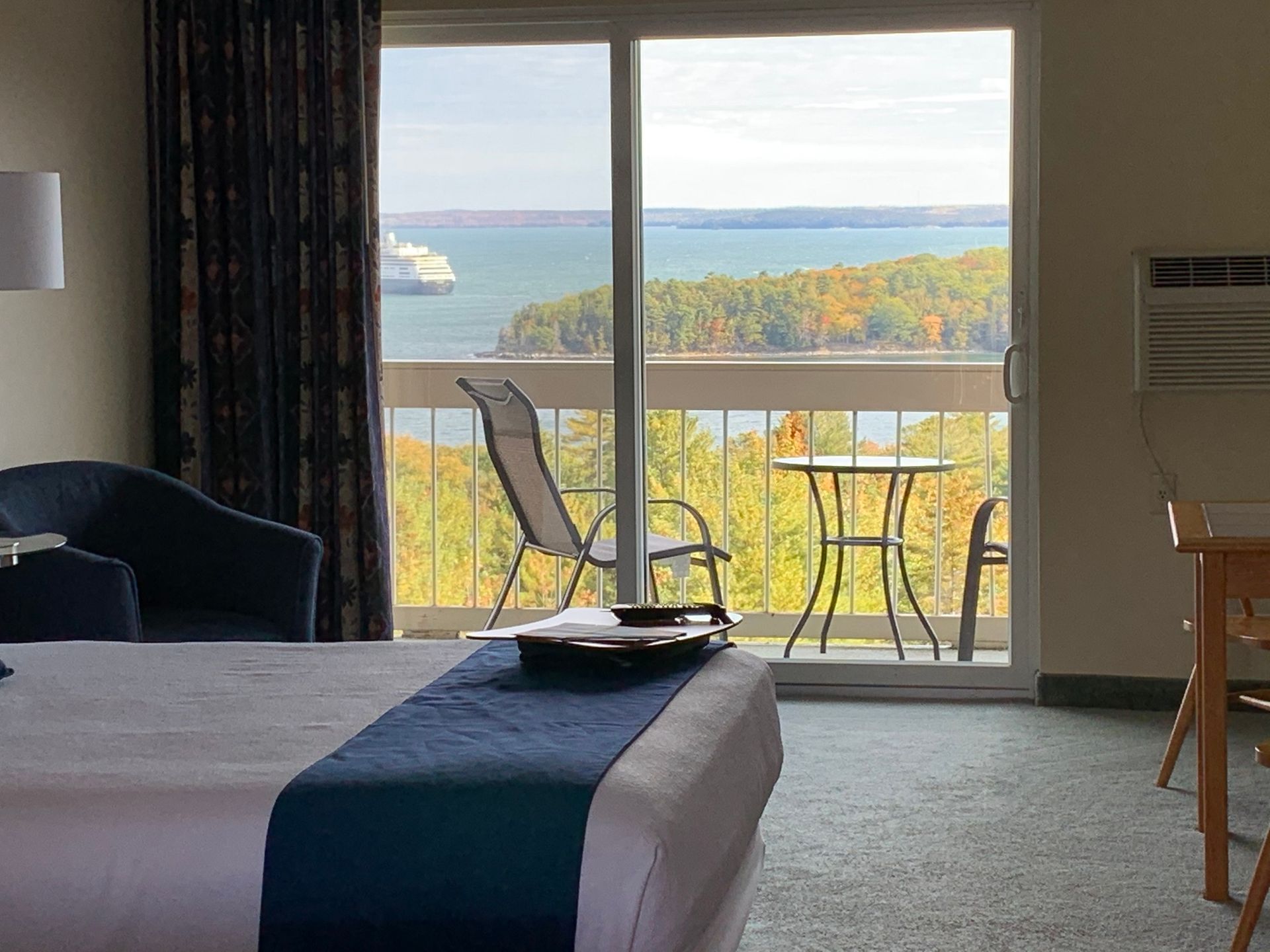 A hotel room with a large bed and a balcony overlooking a body of water.