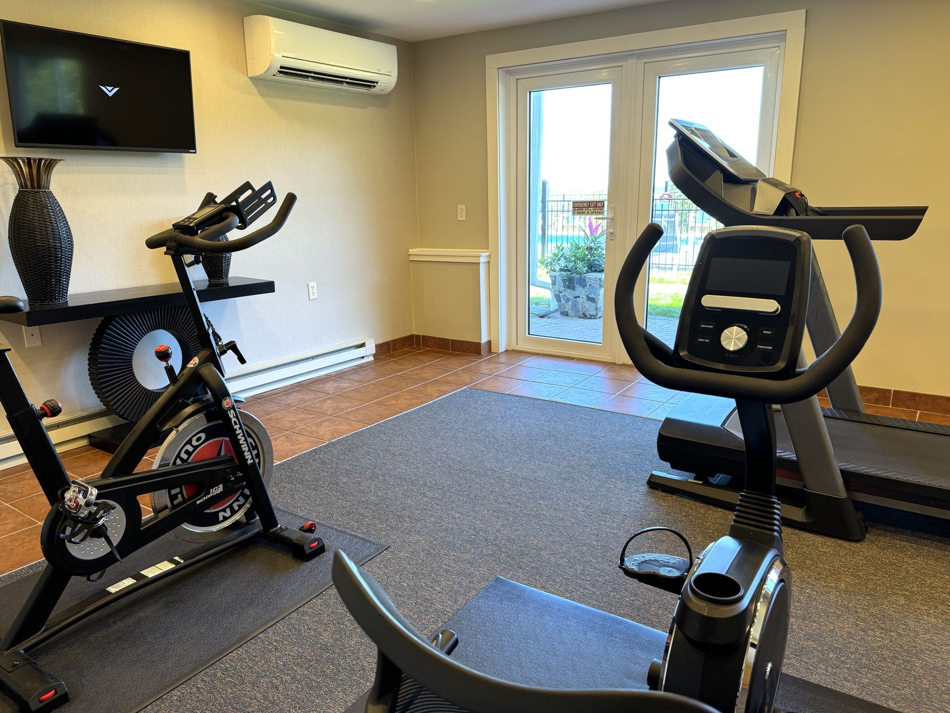 There are two exercise bikes and a treadmill in the room.