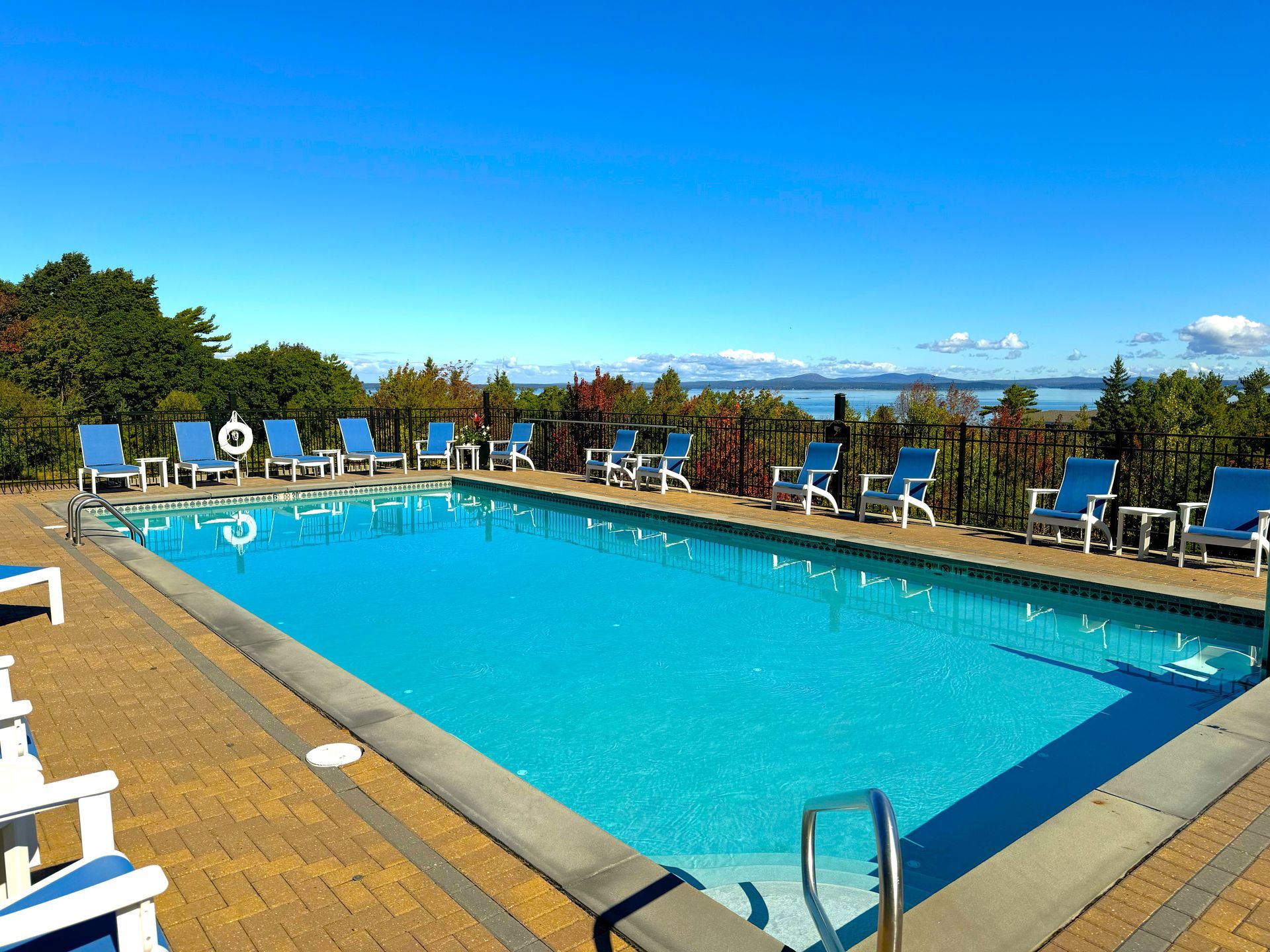 A large swimming pool surrounded by chairs on a sunny day.