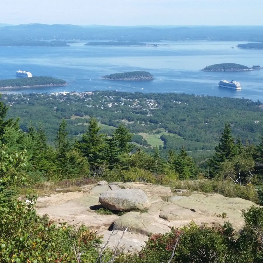 A large rock sits on top of a hill overlooking a body of water