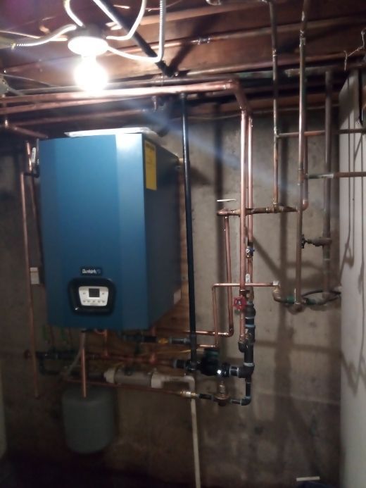 A blue boiler is hanging from the ceiling in a basement