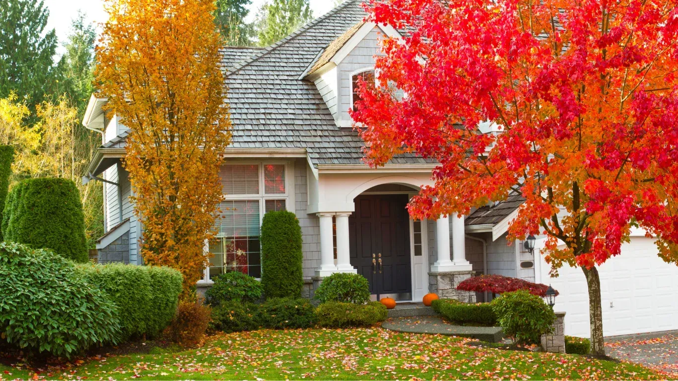 House with gray siding and colorful autumn foliage in front yard.
