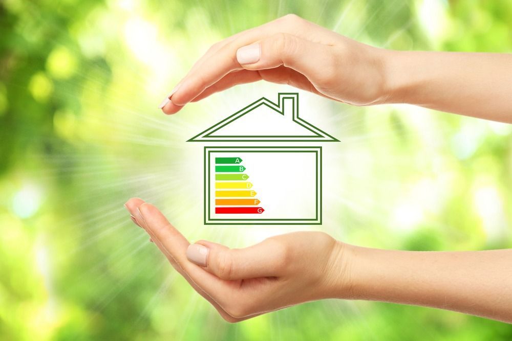 A person is holding a house with an energy efficiency rating in their hands.