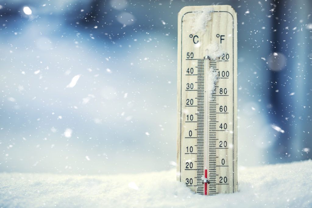 A thermometer is sitting in the snow and shows a temperature of 32 degrees celsius