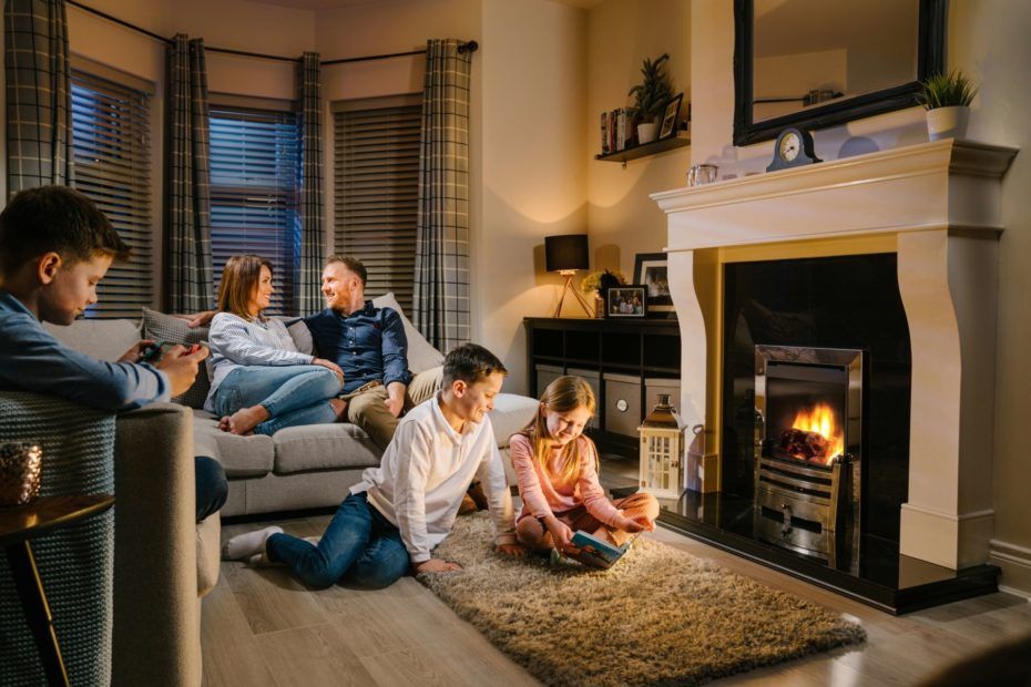 a family sits in front of a fireplace reading a book