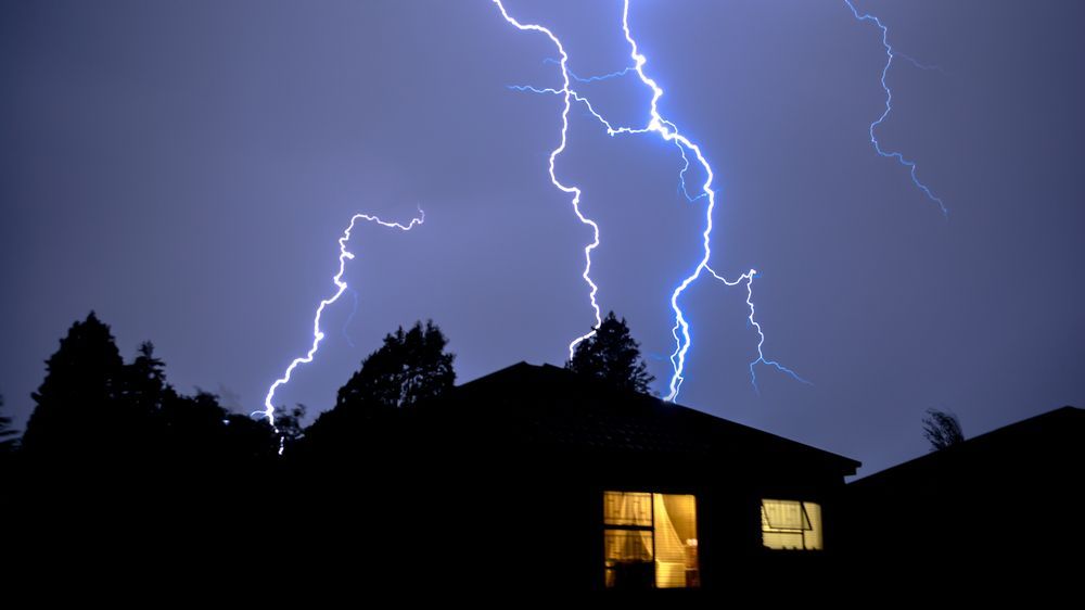 Lightning strikes over a house in the night sky