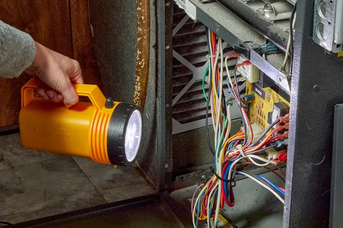 A person is holding a flashlight in front of an electrical box.