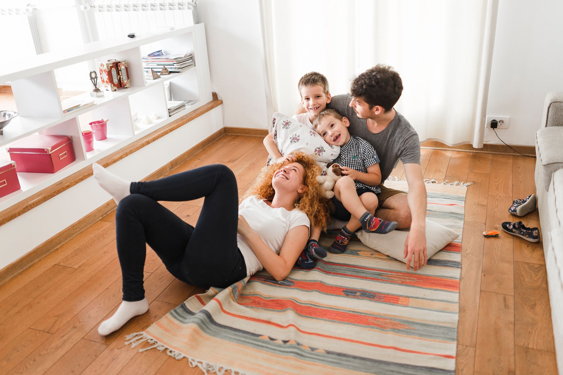 Happy mother and father sitting on floor of home with their two sons