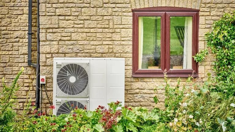 A brick wall with a window and a fan on it.