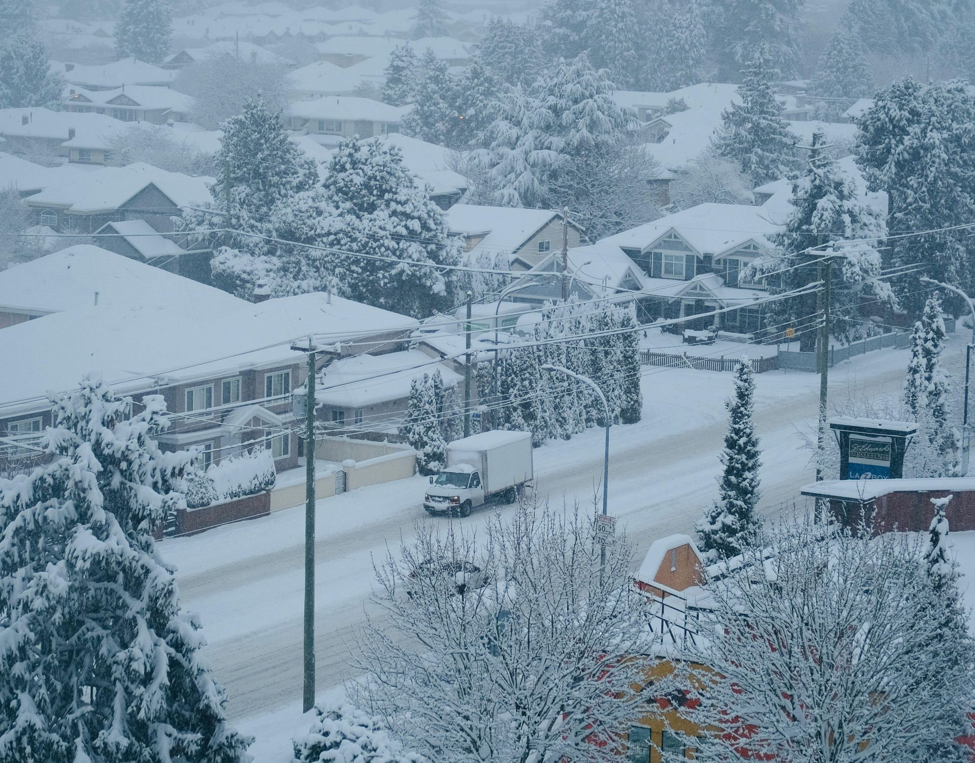 A white truck is driving down a snowy road