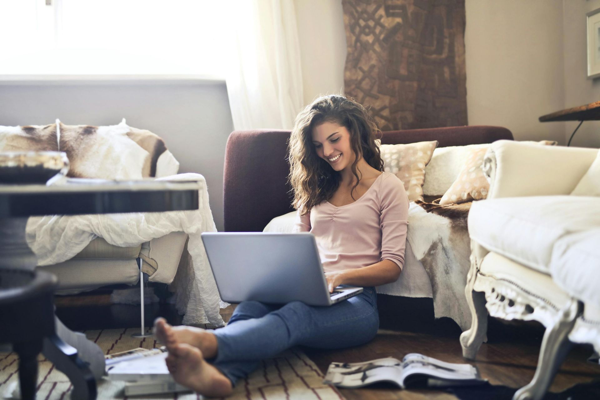 A woman is sitting on the floor using a laptop computer.
