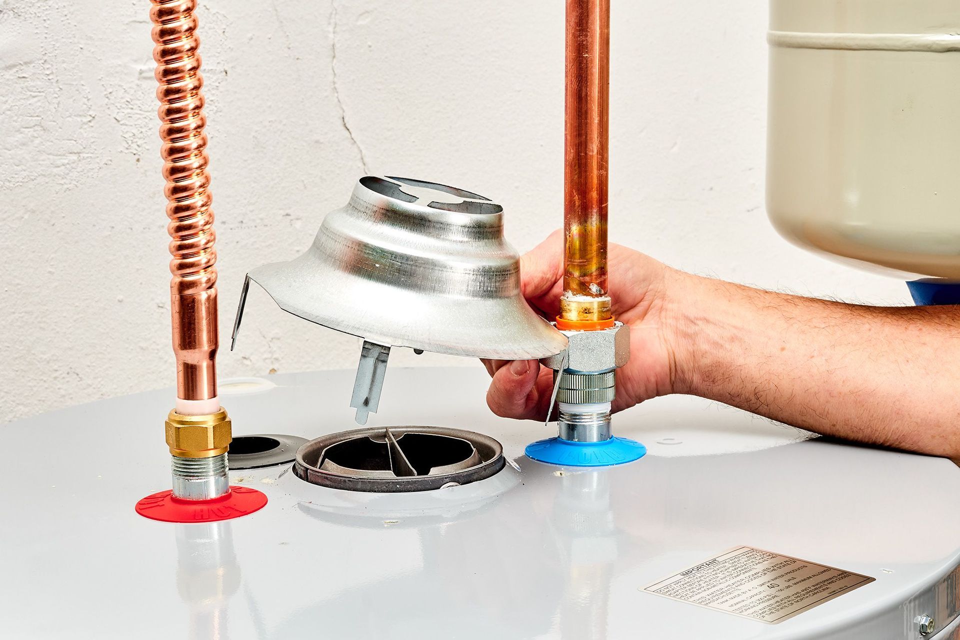 A person is fixing a water heater with copper pipes.