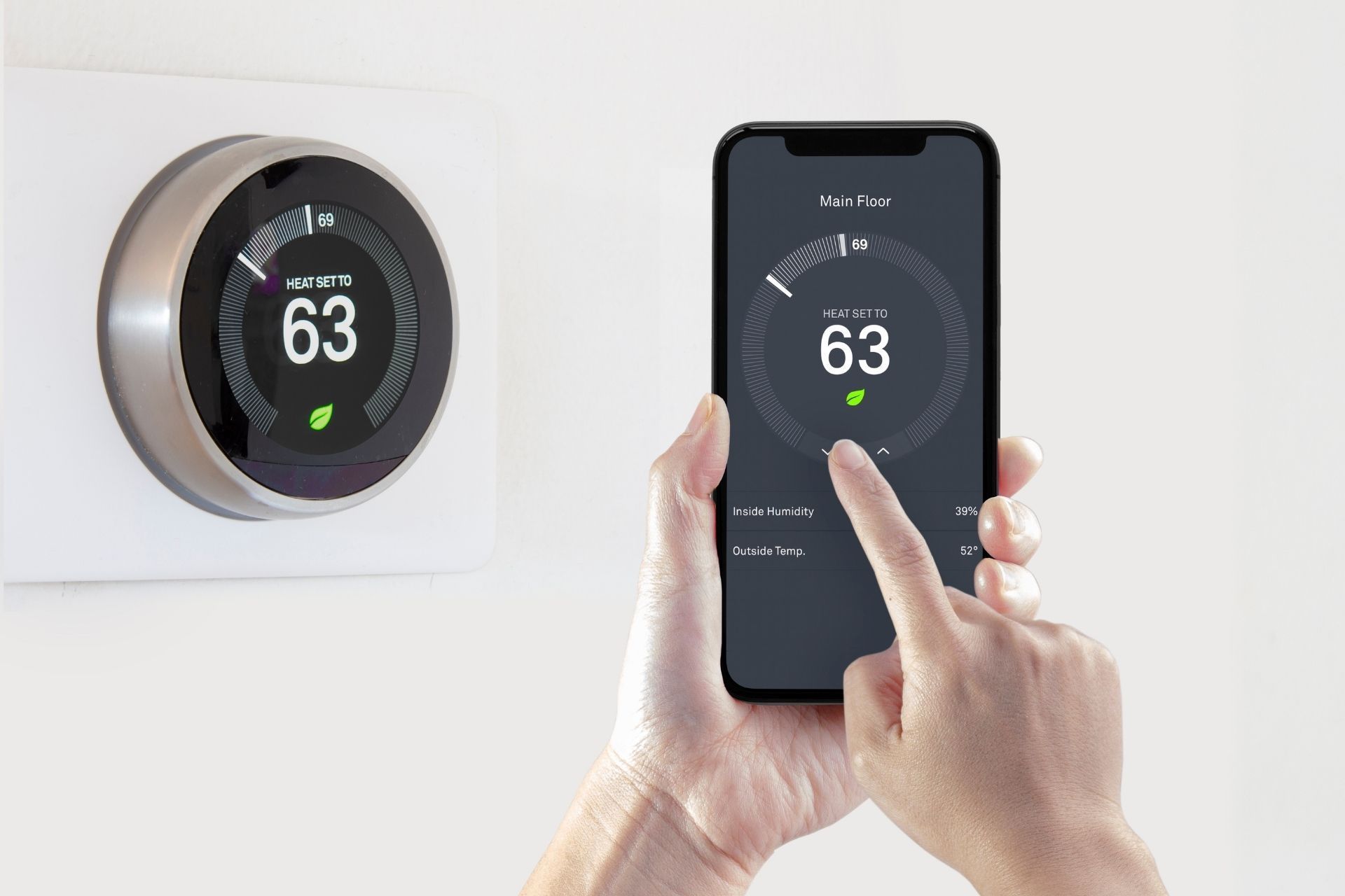 A person is using a smart phone to control a thermostat.