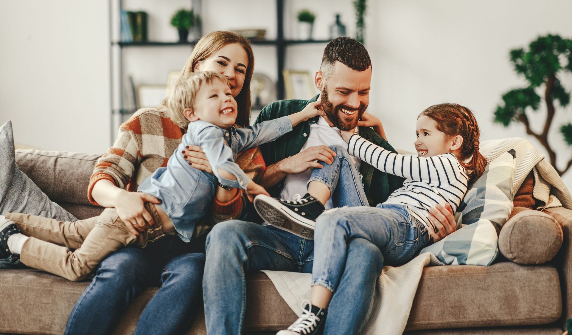 Family of four laughing together on a couch.